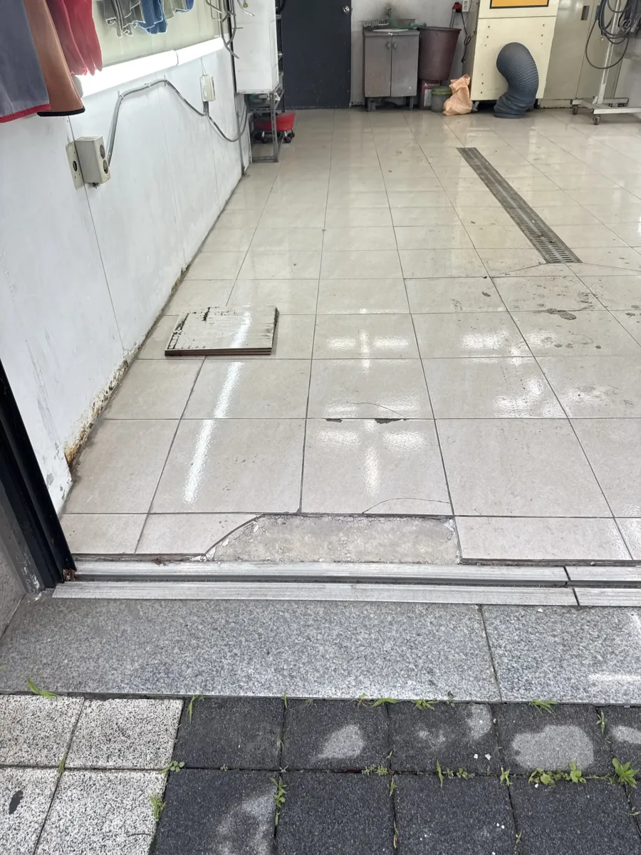 상업공간 출입구 바닥타일 문턱 부위가 깨져 조각이 놓여 있는 실제 현장